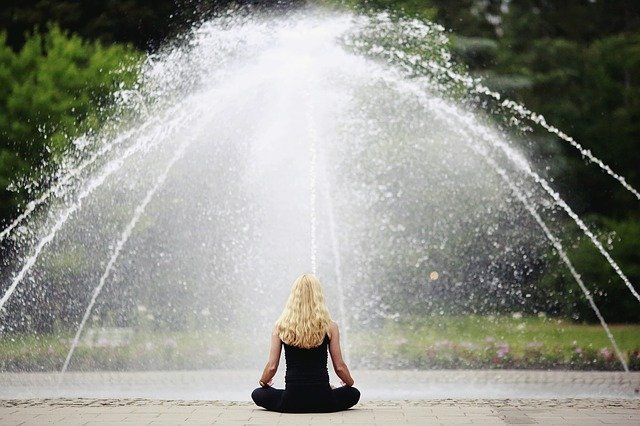 Une femme médite devant une fontaine